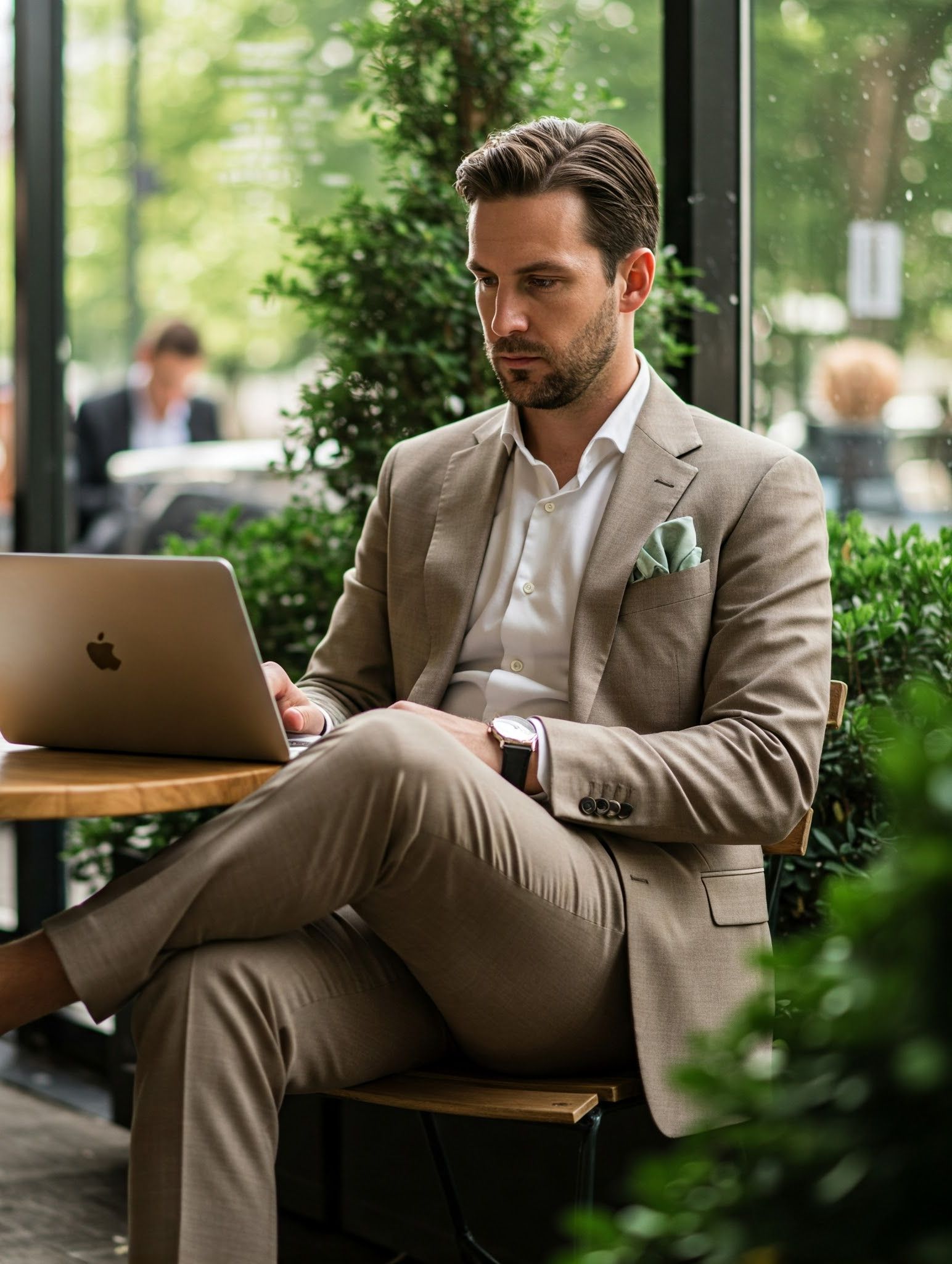Homme en costume taupe travaillant dans un café avec d'autres professionnels élégants