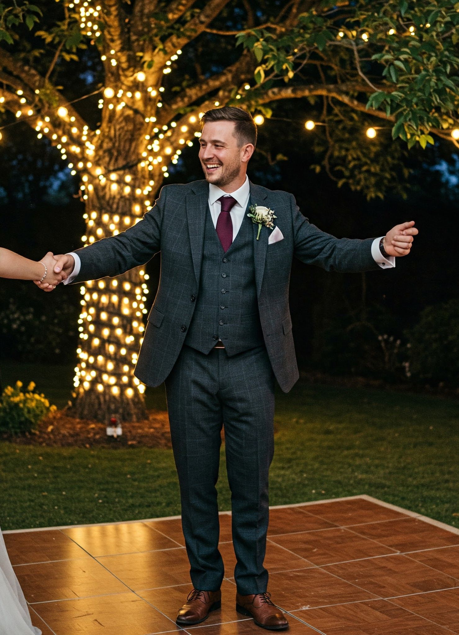 marié en costume anglais gris dansant avec la mariée sous un arbre