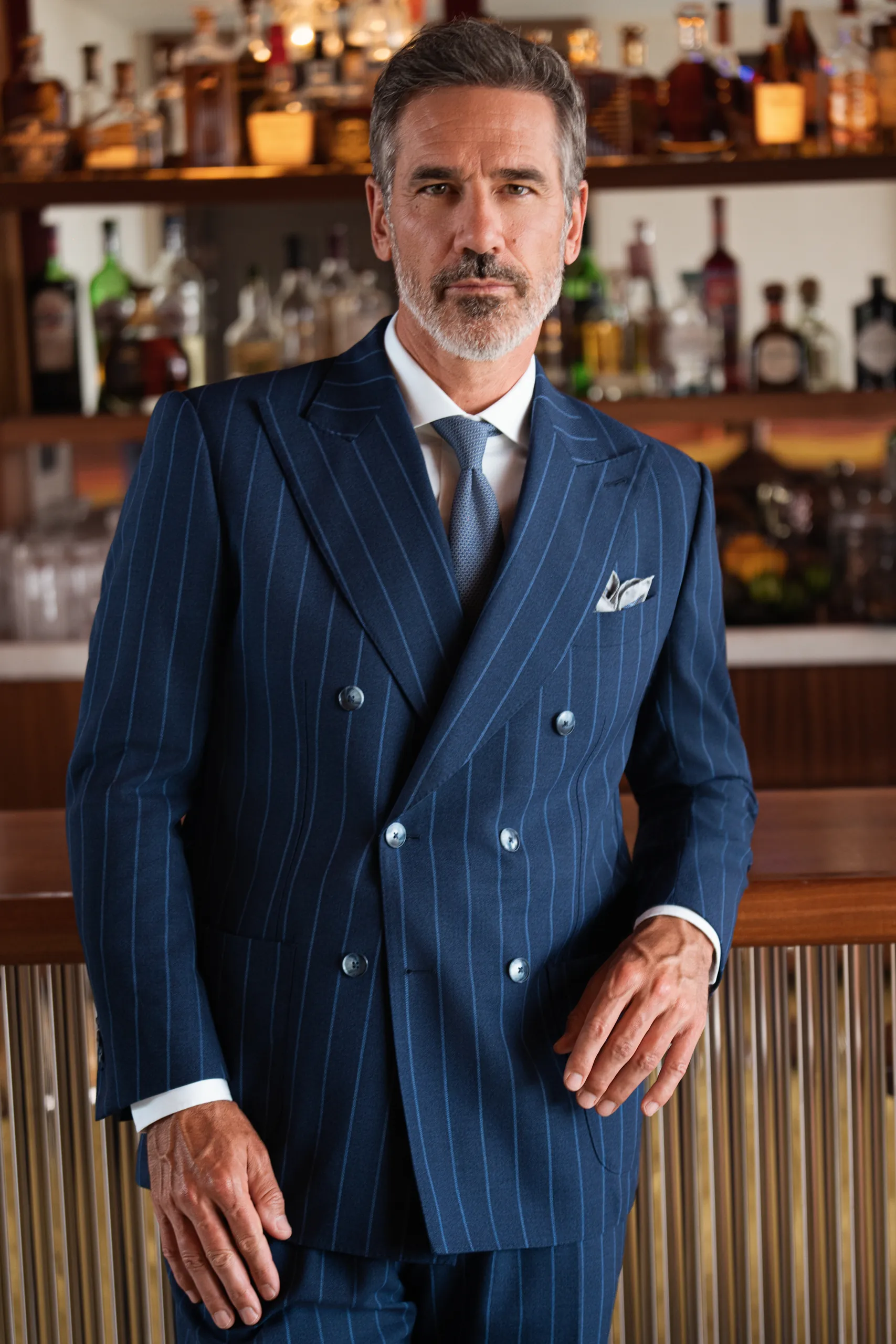 Costume croisé sur mesure bleu marine à fines rayures, devant un bar