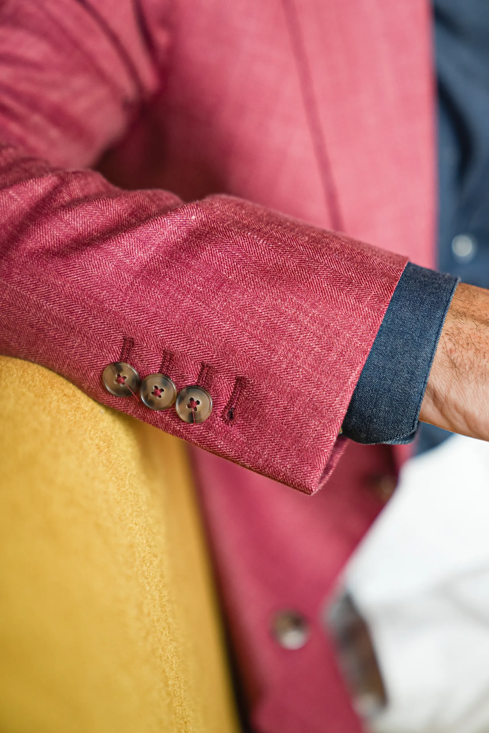 Détail du bas de manche et des boutons d'une veste sur mesure framboise