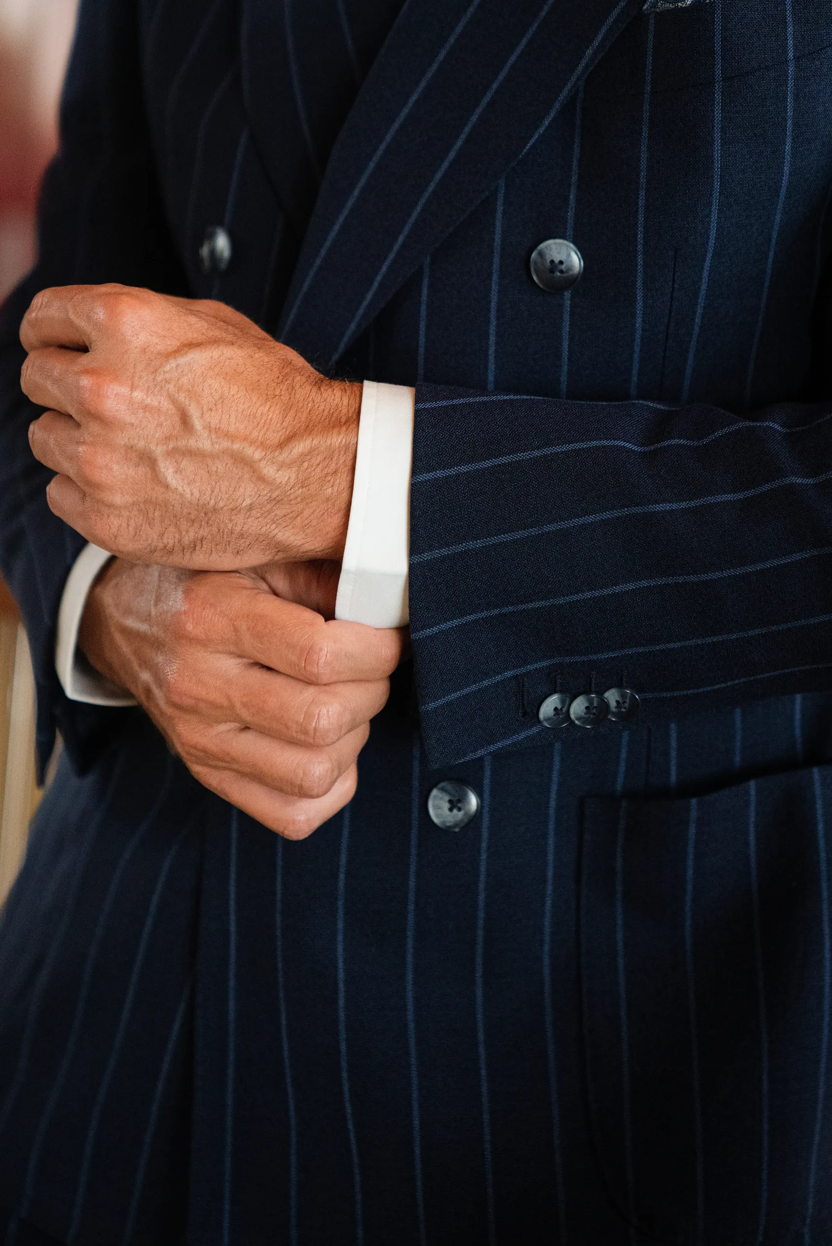 Détail d'un poignet de chemise et d'une veste croisée bleu marine à rayures