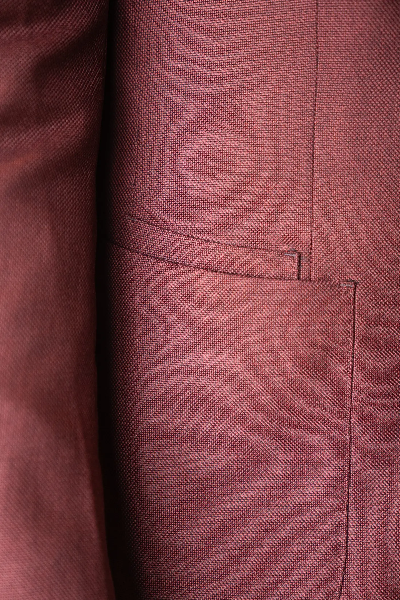 Détail d'une poche à rabat sur une veste sur mesure en tissu bordeaux