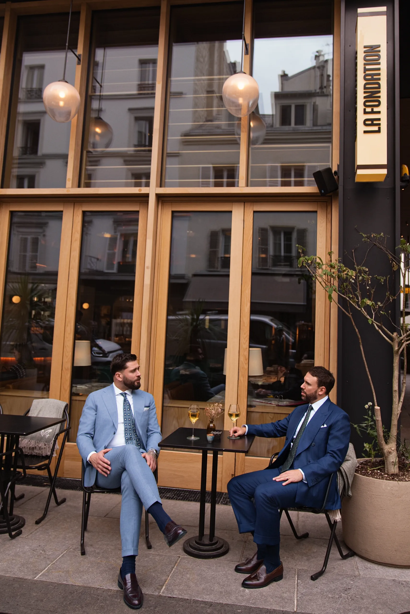 Deux hommes en costume sur mesure attablés en terrasse