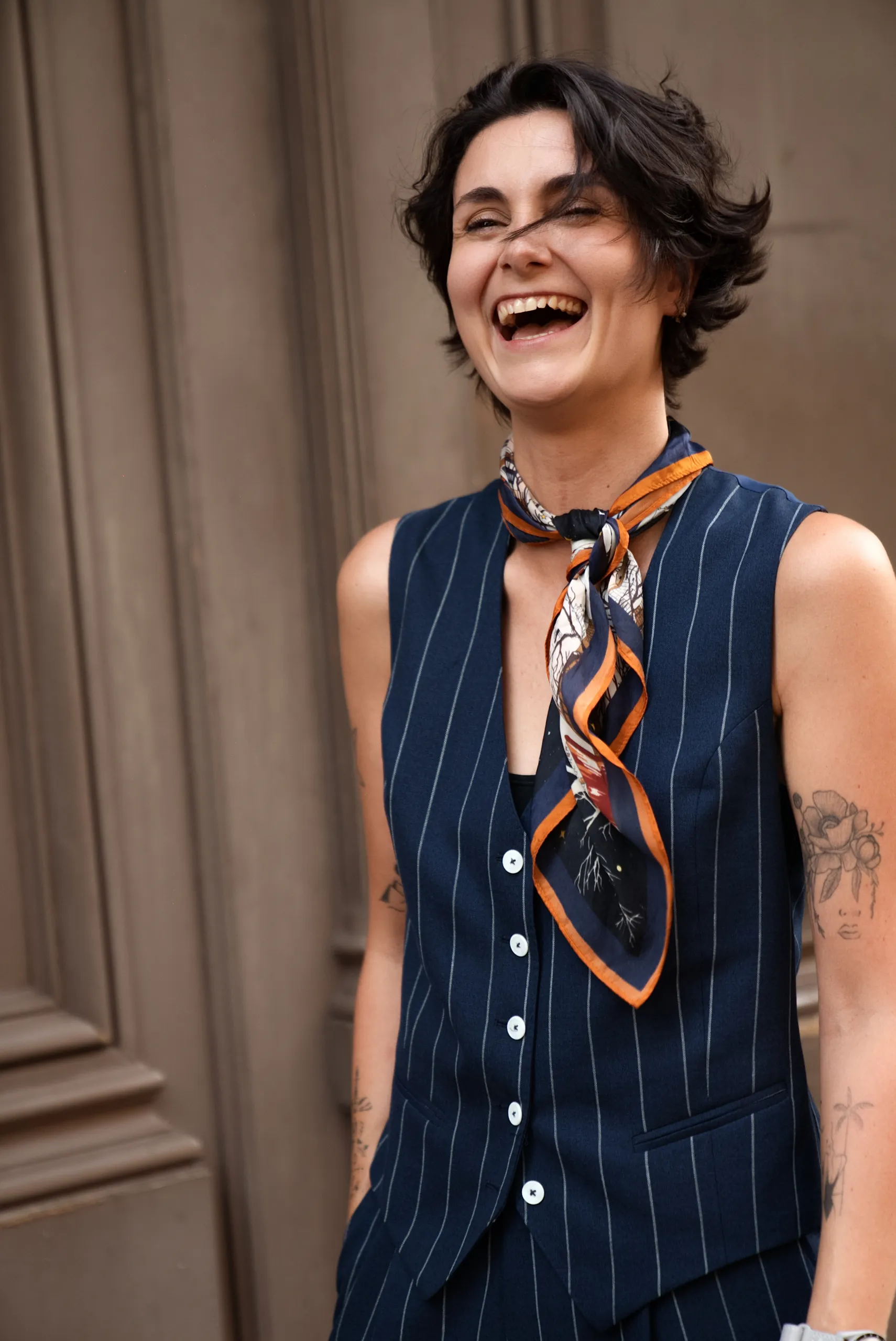 Femme en gilet et pantalon sur mesure bleu marine à rayures, avec un foulard
