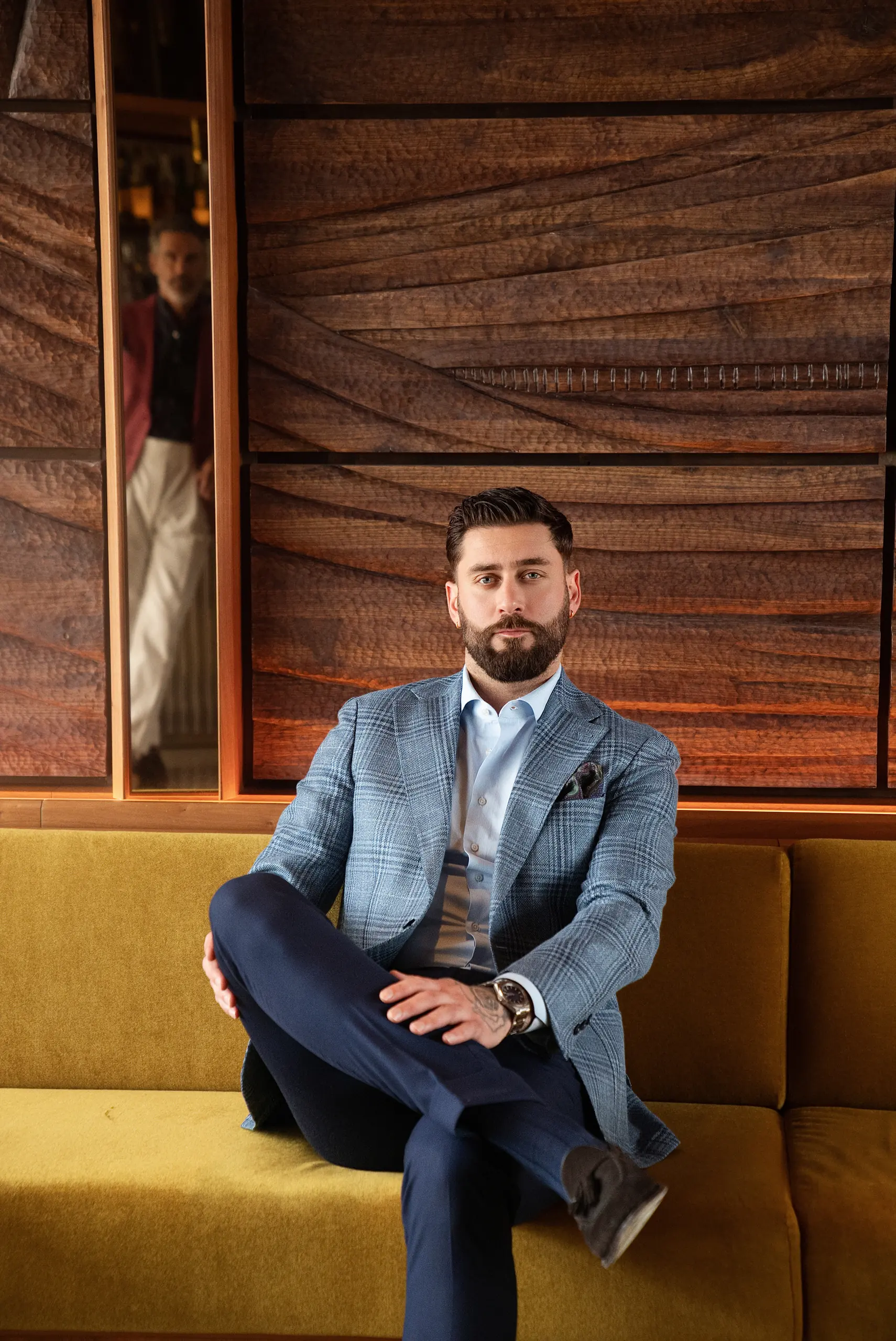 Veste sur mesure à carreaux bleu clair, assis jambes croisées sur une banquette jaune